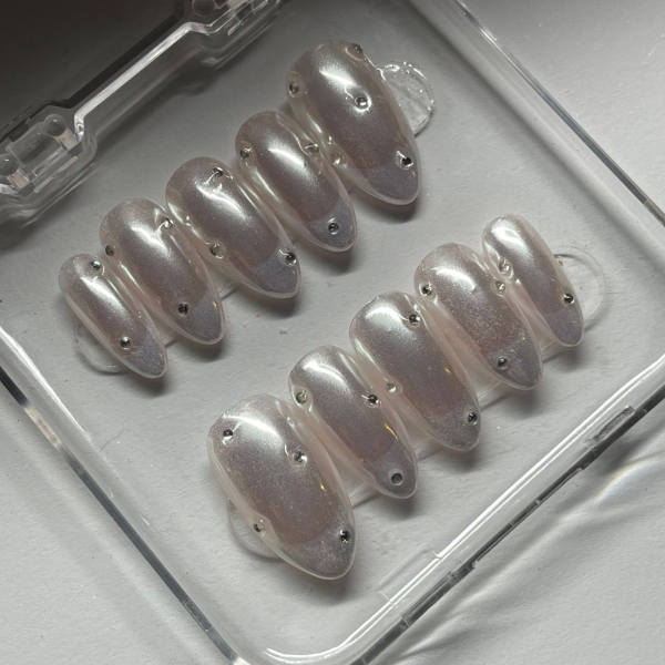A set of pearly fake nails with crystals on them.