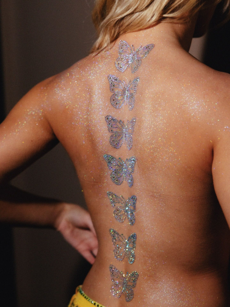 A photo of Zara Larsson's back covered in body glitter and her spine lined with rhinestonestudded butterfly back tattoos.